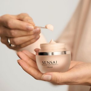 Person, die mit einem Spatel das Produkt Cellular Performance Cream aus dem Tiegel entnimmt